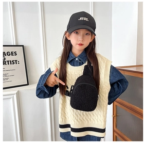 Detail of child wearing a black plush crossbody bag with adjustable strap and zipper closure