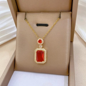 Detailed close-up of a red gemstone rectangle pendant with diamond halo in a gift box