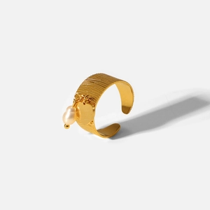 Anello aperto largo in acciaio dorato 18K con ciondoli a cuore e perla su fondo grigio