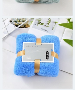 Detailed view of blue coral fleece face towel tied with gold ribbon and gift card