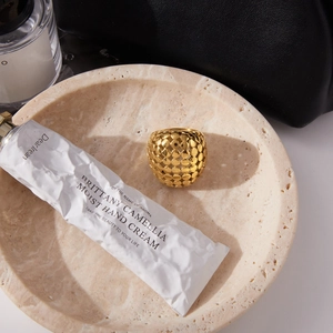 Vue détaillée d'une bague large dorée texturée sur marbre avec un style luxueux