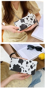 Detail of cow print faux leather wallet with gold zipper and matching wrist strap