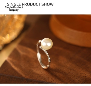 Macro shot of S925 silver bamboo joint ring with a lustrous white pearl on wood