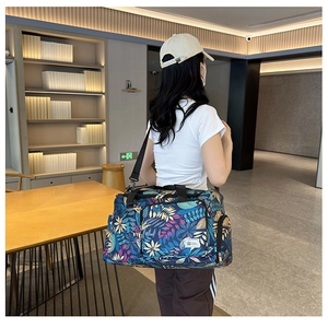 Detail of tropical leaf print travel bag with black adjustable shoulder strap and handles