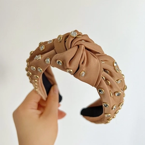 Detail of knotted satin headband with embedded rhinestones and golden metal settings