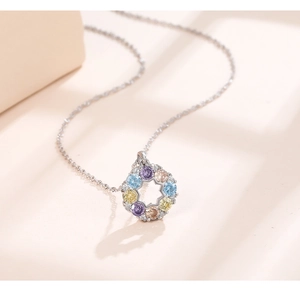 Close-up of circular openwork pendant with multicolor gemstones on a silver chain