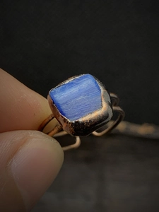 Close-up of a vintage adjustable ring featuring a raw blue gemstone in a bronze setting