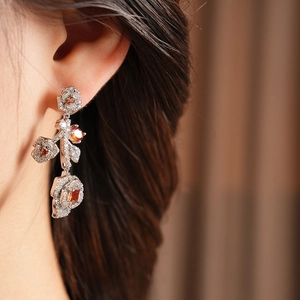 Detail of vintage flower drop earrings with red crystals and micro-pave zircon on model
