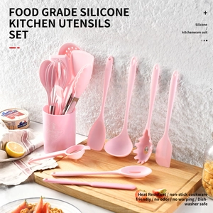 Pink 15-piece silicone kitchen utensil set with storage bucket on wooden board