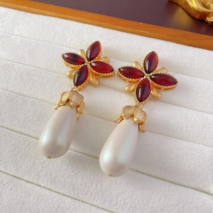 Macro detail of vintage style earrings with red stones and large teardrop pearl drop