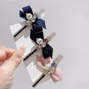 Close-up of three satin bow hair clips featuring rhinestones and a LOVE engraved pearl