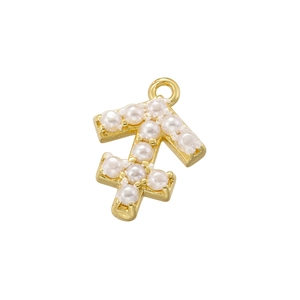 Macro shot of gold Sagittarius zodiac charm with white pearl inlay on white background