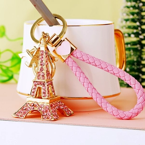 Eiffel Tower keychain with pink rhinestones and a woven cord on a soft background
