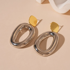 Detailed view of polished two-tone oval earrings with gold square studs and silver hoops