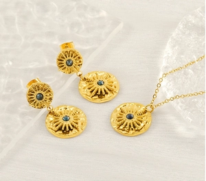 Détail d'un ensemble bijoux soleil doré avec pierres bleues sur un tissu texturé