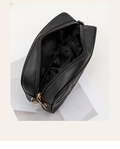 Detailed close-up of black quilted shoulder bag with gold zipper and D-ring hardware