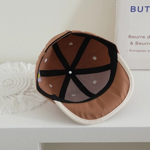 Detailed interior of a brown baby baseball cap showing stitching and ventilation holes