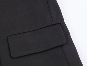 Detail of a black blazer featuring a flap pocket with fine twill texture and stitching