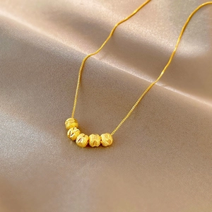 Detail of five gold faceted beads on a fine box chain over champagne satin background