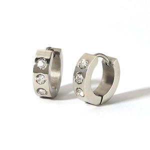 Detail view of silver huggie earrings featuring three vertical clear cubic zirconia stones