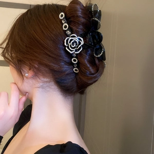 Détail d'une pince à cheveux camélia noir avec strass et nœud en résille sur modèle