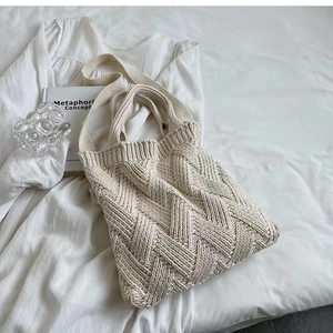 Detail of cream-white knitted tote bag with wave texture on aesthetic white bedding