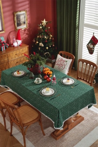 Macro detail of dark green plaid Christmas tablecloth with white pom-pom fringe trim