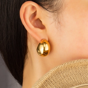 Polished gold-plated teardrop earrings with a chunky C-shape design on a female model