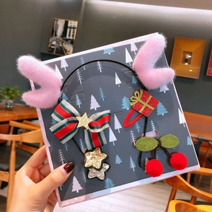 Detail of Christmas headband with pink plush antlers and festive hair clips on a card
