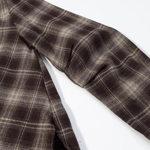 Detail of a brown plaid Y2K cropped shirt showing sleeve texture and fabric quality