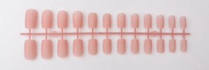 Detailed set of 24 matte pink long square press-on nails on a plastic holder strip