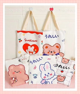 Detail showing cute cartoon bear and bunny prints on cream canvas tote bags with zippers