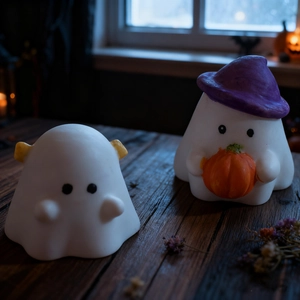 Two Halloween ghost figurines with wizard hat and pumpkin on dark wood table
