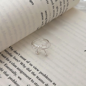 Minimalist 925 sterling silver bow ring with adjustable opening on an open book