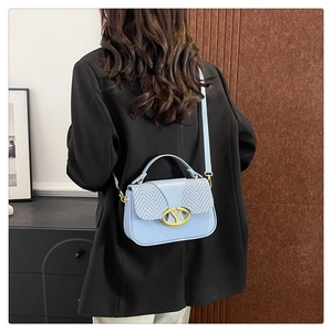 Detail of light blue crossbody bag with chevron weave flap and golden Y metal clasp