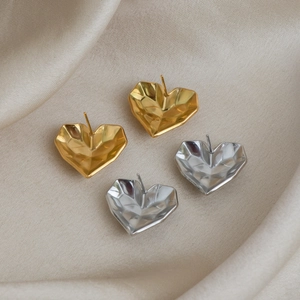 Detail of gold and silver heart studs with geometric facets on silk background