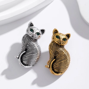 Retro cat brooches in gold and silver metal with textured stripes and green gem eyes