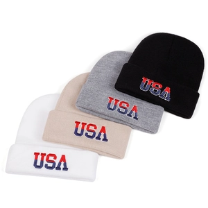 Detail view of USA embroidered knit beanies in white, beige, grey, and black colors