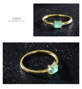 Macro detail of a gold ring featuring a vibrant square green gem and side diamonds