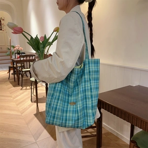 Detail of teal plaid canvas tote bag showing the textured fabric and casual drape