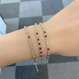 Close-up of three colorful gemstone tennis bracelets on a wrist in silver finish