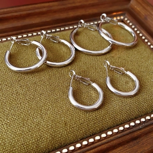 Three pairs of polished silver hoop earrings on green fabric inside a vintage frame