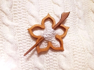 Detailansicht einer hölzernen Schalnadel in Blumenform an einem weißen Strickpullover