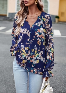 Dettaglio di un'elegante camicetta floreale in chiffon con scollo a V e polsini a campana