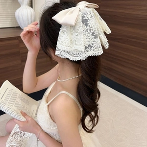 Detailed view of cream lace bow hair claw clip worn on hair with elegant lace textures