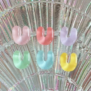 Close-up of small colorful resin U-shaped letter charms for DIY jewelry and hair clips