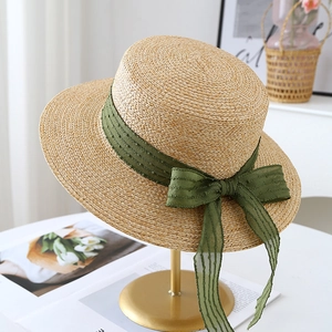 Detailed macro view of a handmade straw hat with an elegant green ribbon bow detail