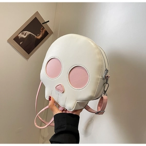 Detail of white skull-shaped crossbody bag featuring pink heart nose and adjustable strap