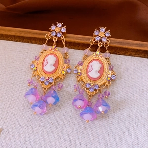 Detail of vintage palace style flower earrings with crystal cameo and purple tassels