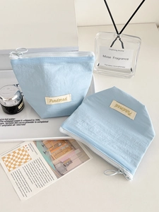 Detail of light blue textured storage bags with round zipper pull on white tray